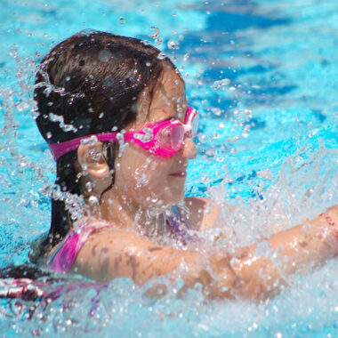 Mädchen mit Schwimmbrille übt schwimmen